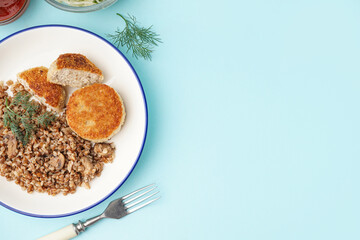 Plate of tasty meat cutlets with buckwheat on blue background