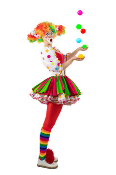 Surprised juggler female clown juggling balls in the circus, woman entertainer as Joker in suit and wig, with clown whiteface makeup. Trickster, jester, pantomime, mime, and a professional actor 