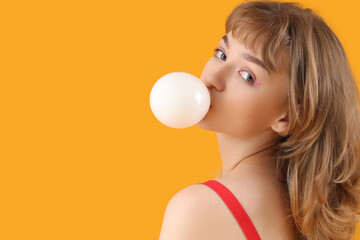 Beautiful young woman with chewing gum on yellow background, closeup