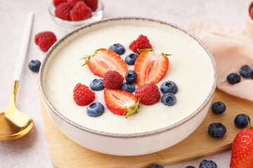 Bowl of tasty semolina porridge with fresh berries on white background