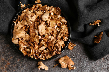 Plate with tasty dried mushrooms on dark background