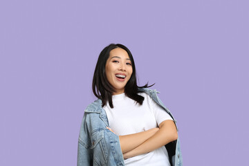 Young Asian woman laughing on lilac background