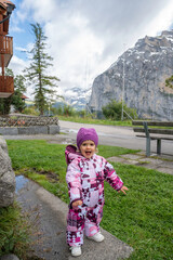 Two-year-old baby in snow gear enjoying a trip to the Swiss Alps, holding the Swiss flag.