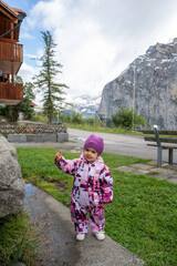 Two-year-old baby in snow gear enjoying a trip to the Swiss Alps, holding the Swiss flag.