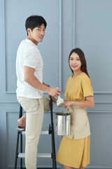 Obraz premium A young male and female couple are painting the walls inside their home.
