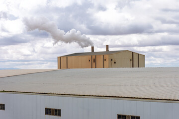 Smoke stacks from an industrial facility against a cloudy sky in Setif City, Algeria.