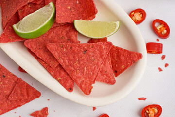 Plate with red nachos, lime and chilli on white background, closeup