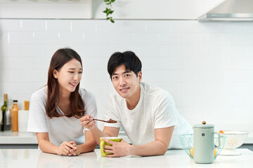 A young Asian couple in the kitchen, enjoying a simple breakfast with milk