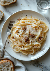 fettuccine with Bolognese sauce on a white plate, a fork and a glass of water next to it,