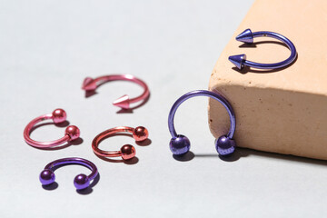 Plaster podium with circular barbells for piercing on grey background