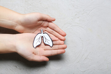Female hands with paper lungs on grey background