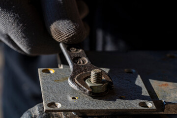 Loosening the nut using a wrench and a vise. Using old spanner wrench and clamp to remove nut from bolt, closeup