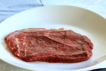 a piece of raw meat, steak on a plate, beef