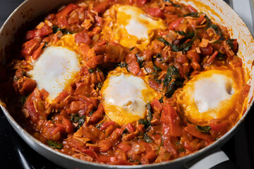 close-up of freshly cooked shakshuka, a flavorful dish with poached eggs in a rich tomato sauce, served in a pan. perfect for a hearty and delicious breakfast.