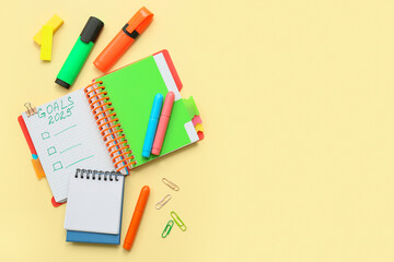 Notebooks with to do plans and stationery on yellow background. New year goals concept