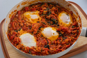 close-up of freshly cooked shakshuka, a flavorful dish with poached eggs in a rich tomato sauce, served in a pan. perfect for a hearty and delicious breakfast.