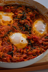 close-up of freshly cooked shakshuka, a flavorful dish with poached eggs in a rich tomato sauce, served in a pan. perfect for a hearty and delicious breakfast.