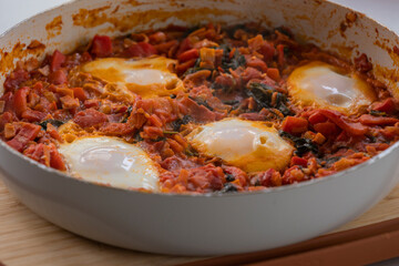 close-up of freshly cooked shakshuka, a flavorful dish with poached eggs in a rich tomato sauce, served in a pan. perfect for a hearty and delicious breakfast.