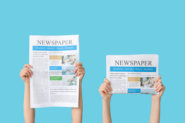 Women holding newspapers against color background