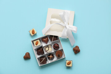 Box with delicious chocolate candies and bow on blue background