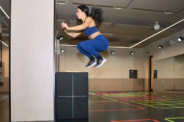 Woman performing box jump exercise in gym
