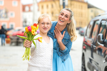 A little girl presents her mother with flowers to celebrate Mother's Day