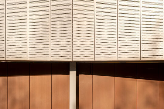 Architectural wall detail with vertical panels in copper and beige tones, minimalist geometry and shadow play perfect for construction, real estate and texture stock