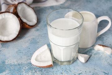 Glass and jug of tasty coconut milk on blue grunge background, closeup