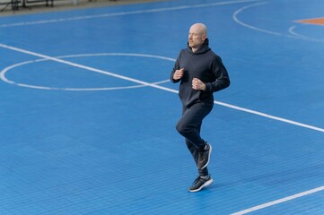 Active man jogging on a vibrant blue sports court