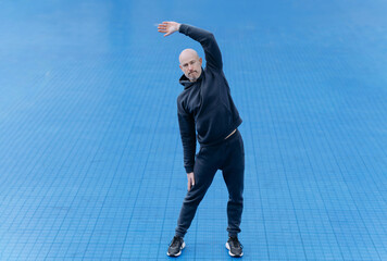 Man Stretching in Athletic Wear on a Blue Surface