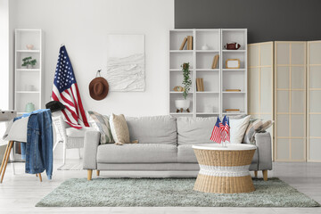 Interior of light living room with grey sofa, coffee table and USA flags