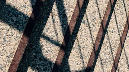 The concrete steps of the bridge descend downwards. In the bright daytime sun, the shadows from the...
