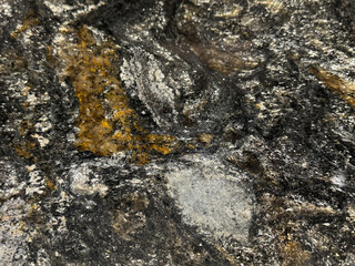 Natural black and white granite slab pattern with orange brown color shades. Shimmering black and grey grains granite with random stone pattern. Natural minerals seamless background texture.