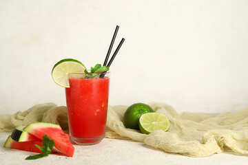 Glass of fresh watermelon juice with lime and mint on white background