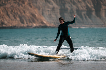Surfing woman riding a wave on a surf board wearing a black wetsuit