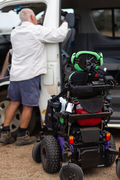 Middle aged man helping his son out of the van into wheelchair