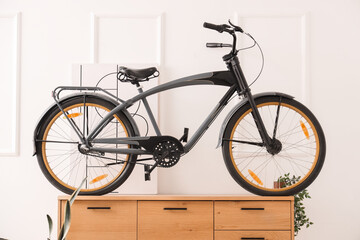 Chest of drawers and bicycle near white wall in room