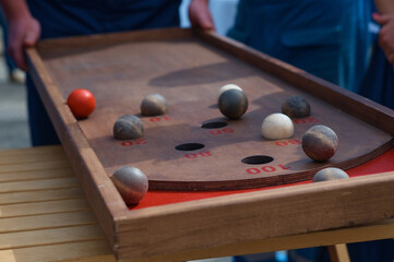 An outdoor board game of Kulbuto played with friends. A competition to see how fast you can get balls into holes. Selective focus