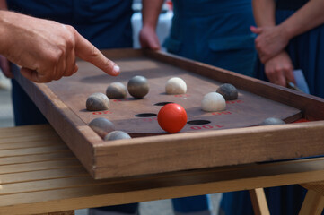 An outdoor board game of Kulbuto played with friends. A competition to see how fast you can get balls into holes. Selective focus