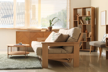 Interior of stylish living room with beige couch, wooden table and commode