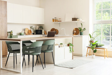 Interior of dining room with table, chairs and counters near white wall