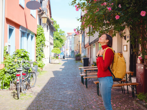 Tourist woman enjoys historic charm of Hochst near Frankfurt, wandering through picturesque streets with old houses and cobblestone alleys, soaking in peaceful atmosphere of old town.