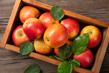Ripe red apples in wooden box on a wooden table