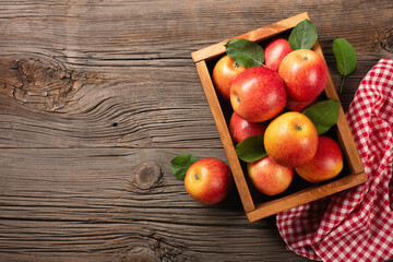 Ripe red apples with branch of white flowers in wooden box on a wooden table