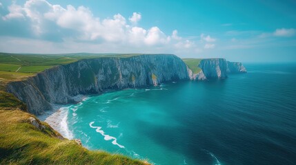 Obraz premium Breathtaking coastal view of rugged cliffs and turquoise waters under a bright blue sky, showcasing nature's stunning beauty