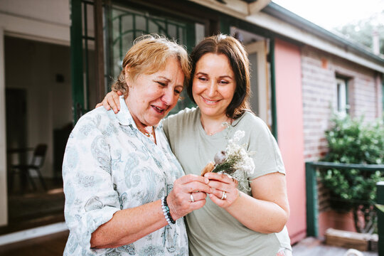 Happy Senior woman and her adult daughter holding flowers for table decor