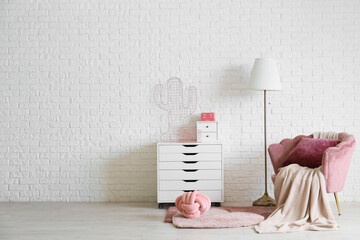 Interior of living room with lamp, pink armchair and drawers