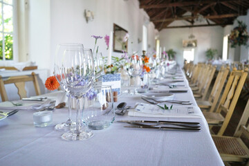 Banquet table in rustic European style. White tablecloth and empty glasses and plates..