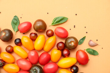 Different fresh tomatoes with basil, garlic and peppercorn on orange background