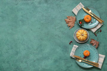 Beautiful table setting with fresh pumpkins, rose hip berries and autumn leaves on green background